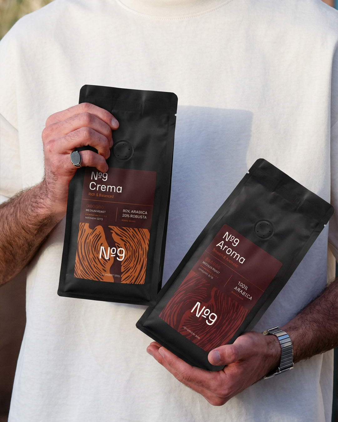 Moški v rokah drži dve 500 g vrečki kave v zrnju No.9 Caffè, Crema in Aroma.