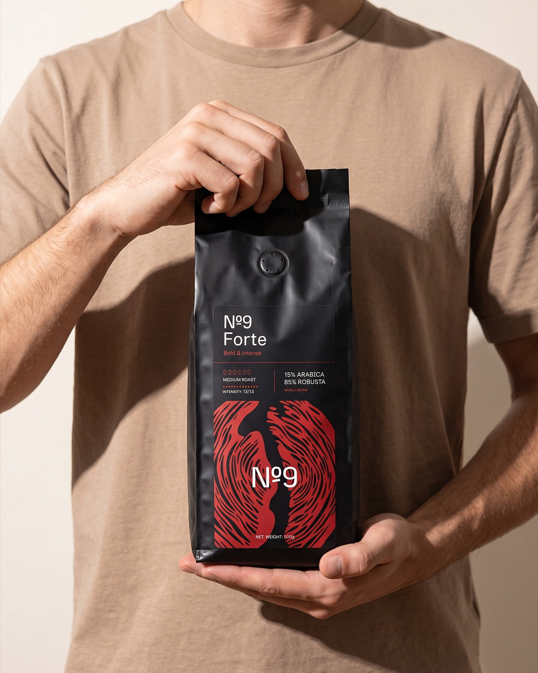 Moški drži 500 g vrečko kave v zrnju No.9 Caffè Forte pred seboj.